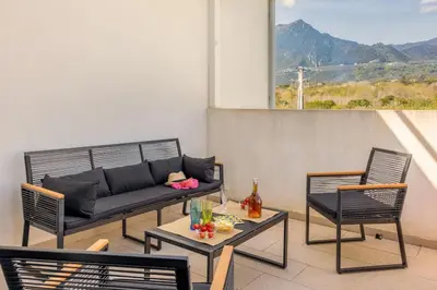 a patio with a couch and chairs and a table at Casa Verde in San-Nicolao