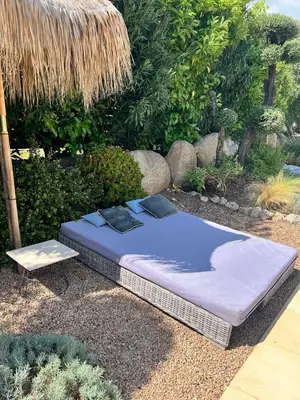 a bed sitting on the ground in a garden at Beautiful villa, pool, sea, 5 bedrooms in Zonza