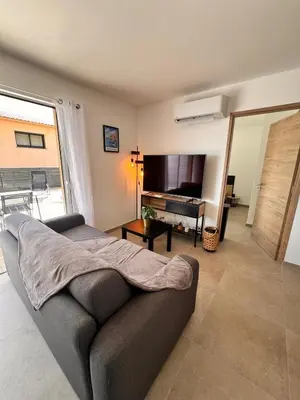 a living room with a couch and a flat screen tv at I Sognu - Charmant Appartement Neuf Proche du Port in Porto-Vecchio