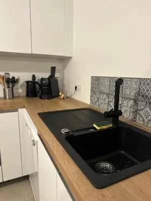 a kitchen with a black sink in a kitchen at I Sognu - Charmant Appartement Neuf Proche du Port in Porto-Vecchio