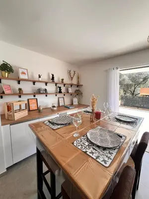 a kitchen with a large wooden table with glasses on it at I Sognu - Charmant Appartement Neuf Proche du Port in Porto-Vecchio