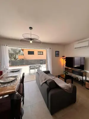 a living room with a couch and a table at I Sognu - Charmant Appartement Neuf Proche du Port in Porto-Vecchio
