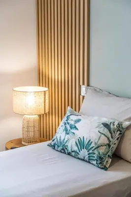 a bed with a blue and white pillow and a lamp at VILLA VITRICCIA - VILLA DE REVE, PISCINE et PLAGE à 7MN A PIED ! in Zonza