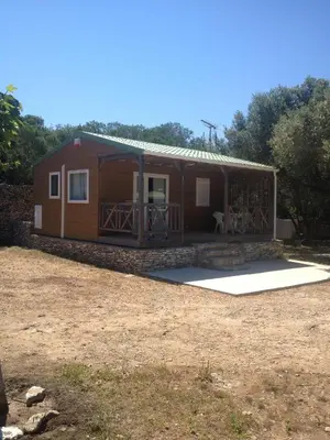 a small cabin with a porch and a yard at Camping Residence Chalet La Pomposa Terrazzoni in Bonifacio
