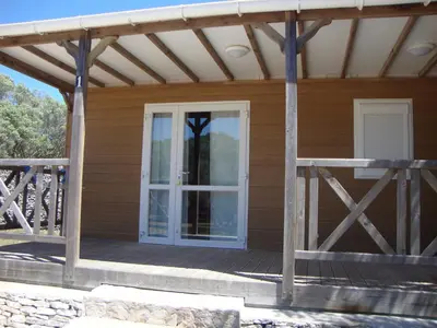 a porch of a wooden house with a door at Camping Residence Chalet La Pomposa Terrazzoni in Bonifacio