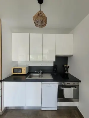 a kitchen with white cabinets and a sink at Studio Port de Porto-Vecchio in Porto-Vecchio