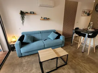 a living room with a blue couch and a table at Studio Port de Porto-Vecchio in Porto-Vecchio