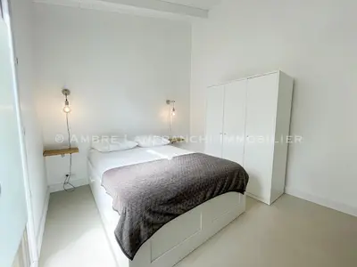 a white bedroom with a bed and a mirror at Maison en pierre - 6 personnes - piscine in Porto-Vecchio