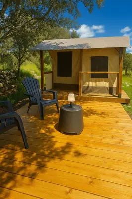 a deck with a tent and two chairs and a table at Camping Mercone in Corte