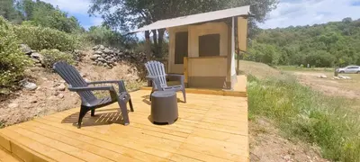 two chairs and a trash can on a wooden deck at Camping Mercone in Corte