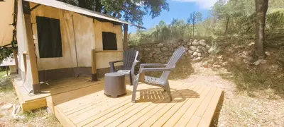 a chair sitting on a wooden walkway next to a cabin at Camping Mercone in Corte
