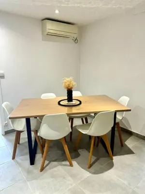 a dining room table with white chairs and a vase with flowers at Maison avec jardin et proche mer in Propriano