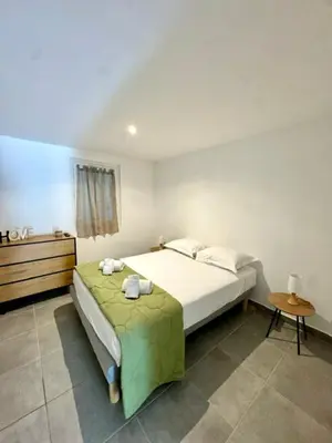 a bedroom with a large bed and a table at Maison avec jardin et proche mer in Propriano