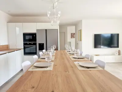 a dining room with a long table with white chairs at Villa neuve piscine privée chauffée Bonifacio in Bonifacio