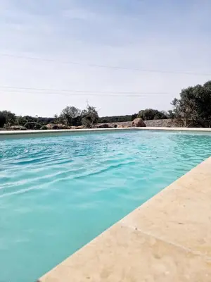 a pool of blue water next to a beach at Villa neuve piscine privée chauffée Bonifacio in Bonifacio