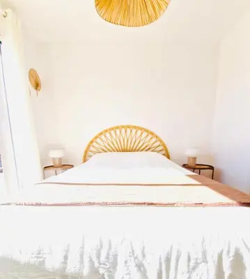 a bedroom with a bed with white sheets and a chandelier at Villa neuve piscine privée chauffée Bonifacio in Bonifacio