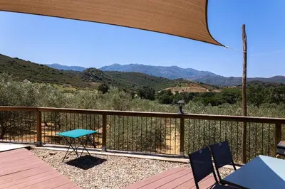a balcony with a table and chairs and mountains at Domaine de Campu in Vallecalle
