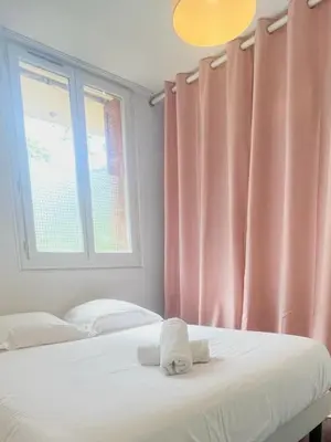 a bedroom with two beds and a window with pink curtains at Ajaccio centre ville joli T2 Grandval in Ajaccio