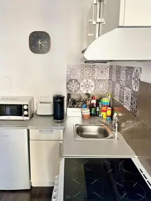 a kitchen with a sink and a clock on the wall at Ajaccio centre ville joli T2 Grandval in Ajaccio
