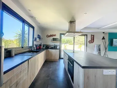 a large kitchen with a counter and a large window at Villa Macchia di Cervi in San-Gavino-di-Carbini