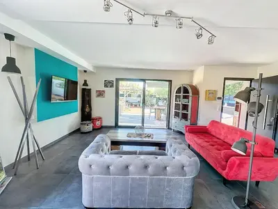 a living room with a red couch and a table at Villa Macchia di Cervi in San-Gavino-di-Carbini