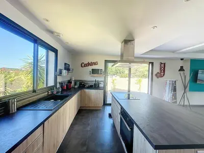 a large kitchen with a counter and a large window at Villa Macchia di Cervi in San-Gavino-di-Carbini