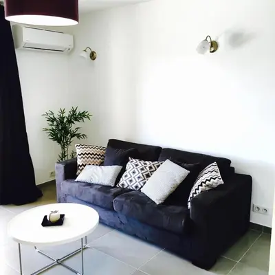 a living room with a blue couch and a white table at Le Diodon De Sagone in Sagone