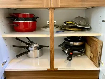 a cabinet filled with pots and pans in a kitchen at Villa de bord de plage in Pinarellu