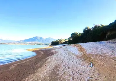 a sandy beach with the ocean and mountains in the background at F2 tout confort, les pieds dans l'eau, PORTICCIO in Grosseto-Prugna