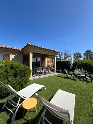 a group of chairs and tables on a lawn at Mini villa,, 700 m de la plage à pieds in Pinarellu