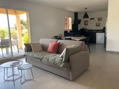 a living room with a couch and a kitchen at Mini villa,, 700 m de la plage à pieds in Pinarellu