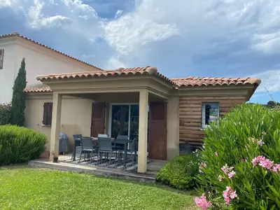 a house with a porch with chairs on a deck at Mini villa,, 700 m de la plage à pieds in Pinarellu