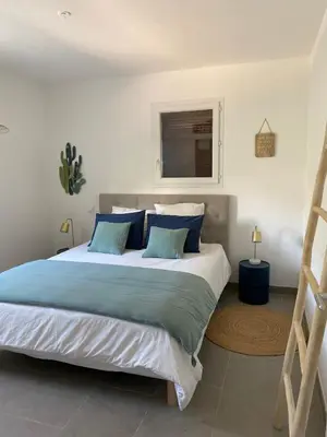 a bedroom with a large bed with blue pillows at Mini villa,, 700 m de la plage à pieds in Pinarellu