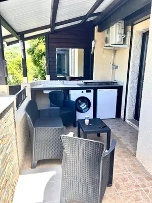 a patio with chairs and a table and a stove at Appartement proche des plages de sable in Grosseto-Prugna