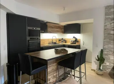 a kitchen with black cabinets and a island with bar stools at Appartement T3, 5 minutes à pied des plages in Ajaccio