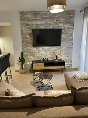 a living room with a tv on a brick wall at Appartement T3, 5 minutes à pied des plages in Ajaccio