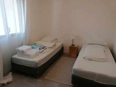 two twin beds in a room with a window at Porticcio grand appartement 3 pièces, 5 minutes de la plage in Porticcio