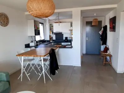 a kitchen and living room with a wooden table in a room at Porticcio grand appartement 3 pièces, 5 minutes de la plage in Porticcio