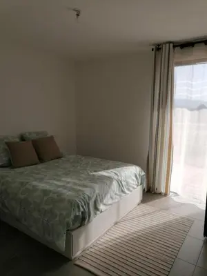 a bedroom with a bed and a large window at Porticcio grand appartement 3 pièces, 5 minutes de la plage in Porticcio