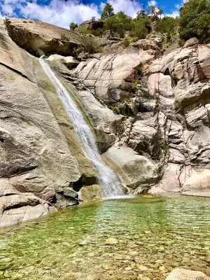 a waterfall on the side of a mountain with a pool of water at Charmant T2 climatisé avec terrasse à 5min des plages in Lecci