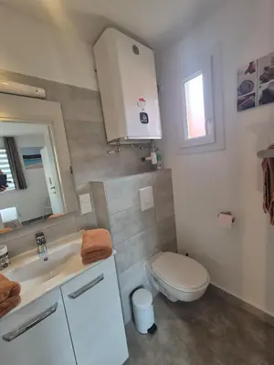 a white bathroom with a toilet and a sink at Charmant T2 climatisé avec terrasse à 5min des plages in Lecci