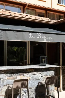 two chairs sitting in front of a store with awning at Hotel Arena le Refuge in Corte