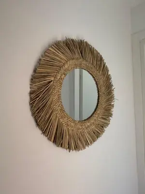 a wicker rattan mirror on a wall at Alizo in Lecci
