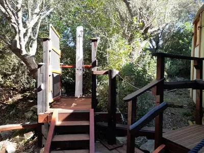 a wooden staircase leading to a deck with trees at yourte de luxe contemporaine in Bonifacio