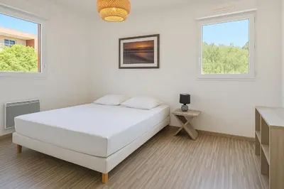 a white bedroom with a bed and two windows at APPARTEMENT T3 65 m2 CENTRE VILLE in Porto-Vecchio