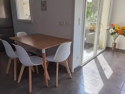 a wooden table and chairs in a room with a window at APPARTEMENT T3 65 m2 CENTRE VILLE in Porto-Vecchio