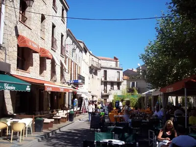 a group of people walking down a street with tables and chairs at APPARTEMENT T3 65 m2 CENTRE VILLE in Porto-Vecchio