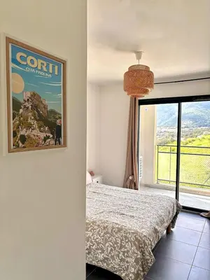 a bedroom with a bed and a poster on the wall at Charmant t2 avec terrasse in Corte
