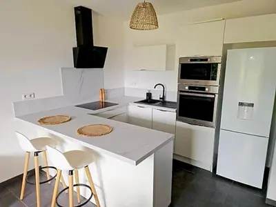a kitchen with a counter with stools and a stove at Charmant t2 avec terrasse in Corte