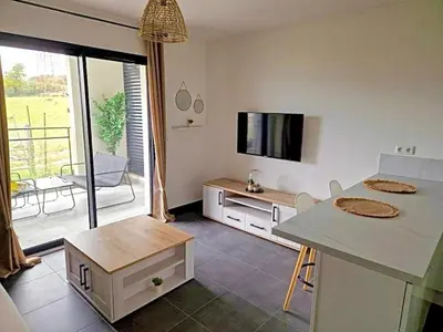 a living room with a table and a tv and a kitchen at Charmant t2 avec terrasse in Corte